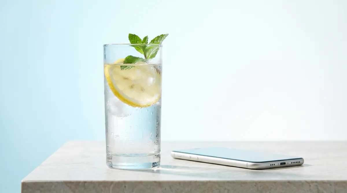 A glass of water beside a smartphone showing a daily hydration goal